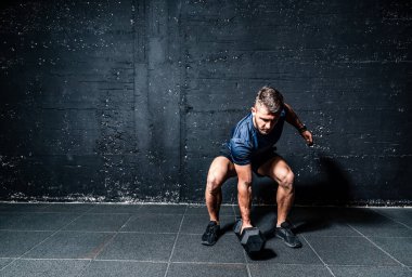Young strong serious sweaty focused athlete fit muscular man with big muscles holding heavy kettlebell weight barbell iron for swing crossfit training hard core workout in the gym