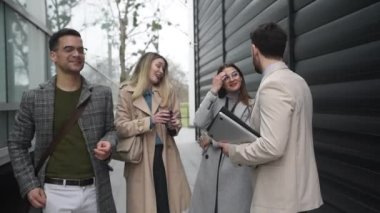 Ofis binasının önünde duran genç iş adamları, başarı hakkında deneyim paylaşımı, iş fikirleri ve çalışanların ve müşterilerin çalışma koşullarını iyileştiren öneriler hakkında konuşuyor.