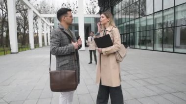 Ofis binasının önünde duran genç iş adamları, başarı hakkında deneyim paylaşımı, iş fikirleri ve çalışanların ve müşterilerin çalışma koşullarını iyileştiren öneriler hakkında konuşuyor.