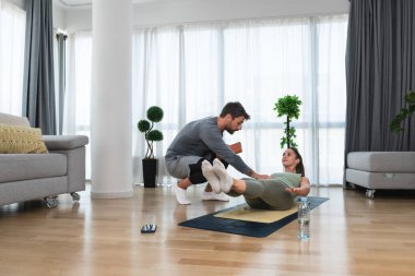 Kişisel fitness eğitmeni olan bir kadın. Çift birlikte egzersiz yapıyor. Spor yapan kadın ve erkek evde spor yapıyor. Daha iyi bir yaşam için koç eğitmeniyle sağlıklı yaşam tarzı eğitimi