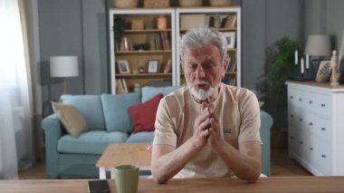 Kendine güveni tam, orta yaşlı yakışıklı bir adam kameraya bakıyor. İnternetten iş ortaklarıyla konuşuyor. Web kamera görüntüsü olgun büyükbaba arkadaşlarıyla görüntülü konuşma yapıyor..