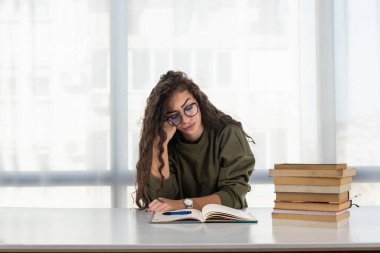 Çok çalıştım. Yorgun genç bayan kitap dolu bir şekilde evdeki masasında oturuyor. Avuç içlerine saklanmış, baş ağrısı çekiyor. Kendini kötü hisseden bitkin bir kız öğrenci konsantrasyonunu kaybediyor.