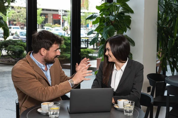 stock image Two young business people having a successful meeting at restaurant. Businessman and businesswoman sitting in cafeteria working together on laptop computer