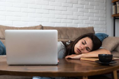 Dizüstü bilgisayarı olan yorgun, bitkin, serbest çalışan bir kadın, projeyle ilgili problemler, depresyonda olmak, oturma odasında tembellik. Stresli kız öğrenci çalışmaktan yoruldu.