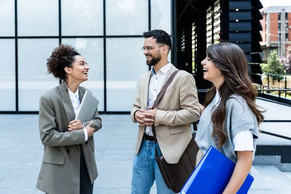stock image Quick briefing before meeting. Group of cheerful young successful business people talking to each other while walking outdoors. Office workers experts exchanging ideas and solutions