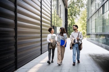 Genç iş adamları grup işkadını toplantılar arasında ofis binasından binaya yürür çalışanları daha iyi ve daha başarılı bir iş ve sunum için eğitirler.