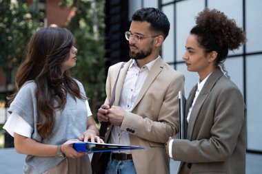 Ofis binalarının önünde yürüyen bir grup iş arkadaşı iş planını tartışıyor. İş adamları pazarlama uzmanları fikirler ve pazarlama taktikleri hakkında konuşuyor