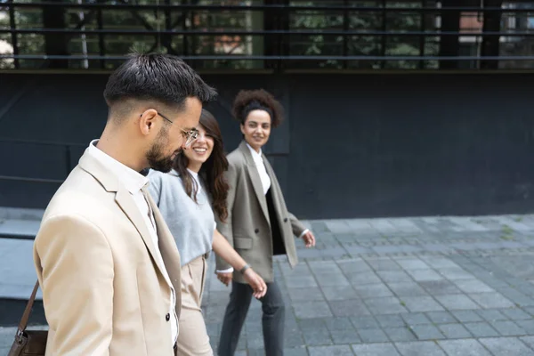 Group of coworkers walking outside in front of office buildings discuss about business plan. Businesspeople marketing sale experts talking ideas and marketing tactics