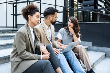 Bir grup iş adamı ofis binalarının önünde yürüyor. İş adamı ve iki iş kadını, başarılı bir strateji ve pazarlama için deneyim ve taktik paylaşıyorlar. İşçiler mola veriyor..