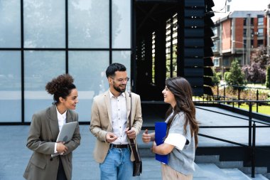 Bir grup iş adamı ofis binalarının önünde yürüyor. İş adamı ve iki iş kadını, başarılı bir strateji ve pazarlama için deneyim ve taktik paylaşıyorlar. İşçiler mola veriyor..