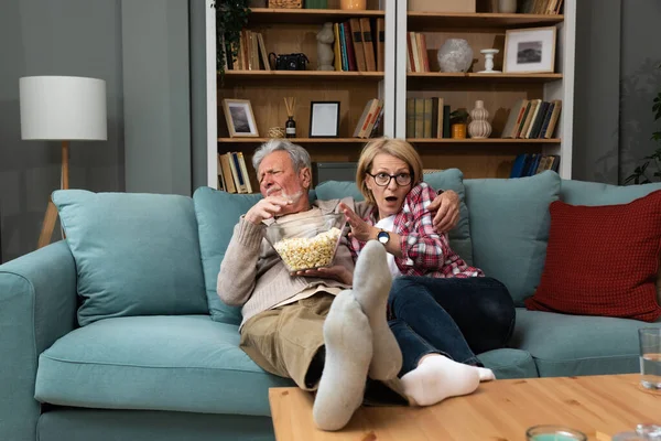 stock image Old retired age couple watching TV at home, old mature couple cheering sport games competition together with laugh smile victory on sofa couch at living room home. Senior man and woman movie night.