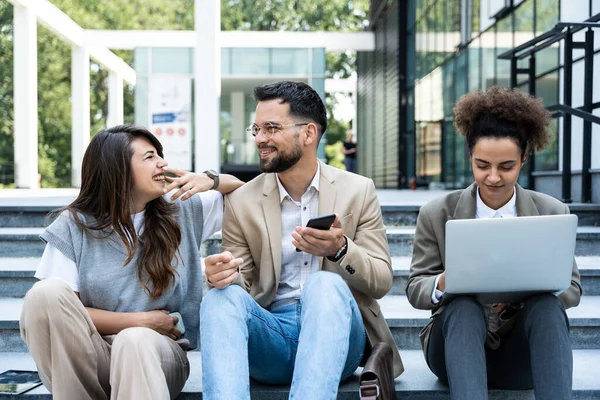 stock image Group of business people walk outside in front of office buildings. Businessman and two businesswomen sharing experience ideas and tactic for successful strategy and marketing. Workers taking a break.