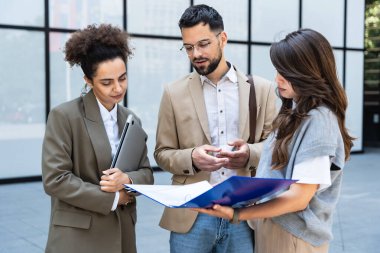 İş adamlarından oluşan bir ekip ofis binasının önünde konuşuyor. Personel toplantısı. Çalışanların motivasyon konuşması hakkında ofis çalışanlarını bilgilendirme toplantısı. İş adamı ve iş kadını fırsatları tartışıyor