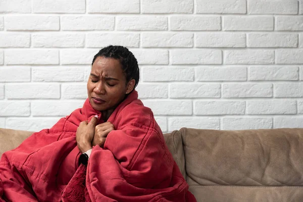 生病的年轻非洲妇女感觉冷盖毯子坐在坐在毯子上 生病的黑人女孩颤抖冰冻温暖在家里包裹着格子 没有中央供暖问题 发烧温度流感的概念 — 图库照片
