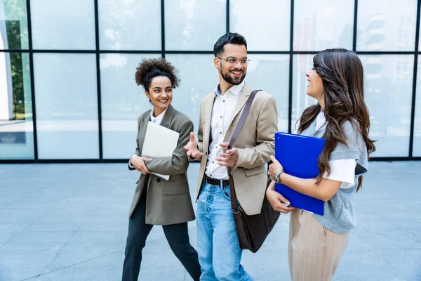 Stock image Team of business people talking in front of office building. Staff meeting quick briefing of office workers on motivational speech for employees. Businessman and businesswomen discussing opportunities