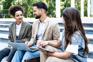 Ofis binasının önünde bir grup iş adamı iş arkadaşlarıyla dedikodu yapıyor. Genç işçiler işe ara verdiklerinde patronun dedikodusunu yapıyorlar.