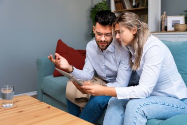 Tablet istatistiklerine bakan endişeli karı koca iş adamları hayal kırıklığına uğramış banka hesaplarının olumsuz durumunu hissediyorlar. Merkez ofisteki e-bankacı iş adamları kötü haber e-postalarını vurguladılar