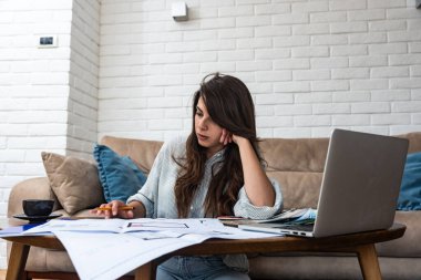 Yeni bir proje üzerinde çalışan serbest çalışan genç bir iç mimar kadın. İşletme sahibi kadın mimar kağıt planları ve dizüstü bilgisayar çözümlerini kontrol ediyor.