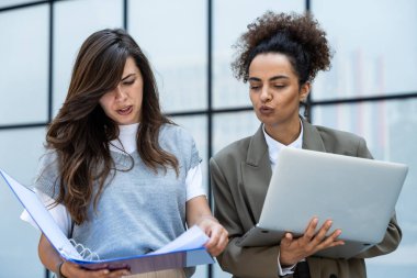 İki iş adamı, çalışan kadınlar, gülümseyen ve birbirlerine bakan biri dizüstü bilgisayar, diğeri ise istatistiksel planlar ve belgeler. Ofis binasının dışında tartışan iki iş arkadaşı..