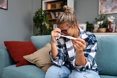 Bekar, üzgün bir kadın, evdeki oturma odasındaki koltukta oturan hamile ya da değil, kadın, pozitif ya da negatif testlerden şikayetçi..