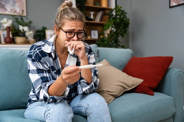 Bekar, üzgün bir kadın, evdeki oturma odasındaki koltukta oturan hamile ya da değil, kadın, pozitif ya da negatif testlerden şikayetçi..