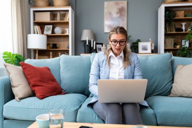 Küresel işletme şirketinin iş kadınları ortakları, müşterileri veya personel üyeleriyle internet üzerinden görüşme yapıyorlar. Üst katta resmi giysiler, alt katta eşofman altı.