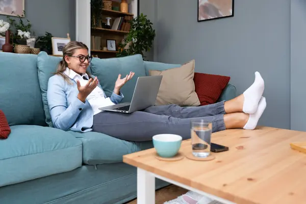 Business women owner of global business company having online video call conversation meeting with partners, clients or staff members on laptop computer wearing formal wear above and sweatpants below
