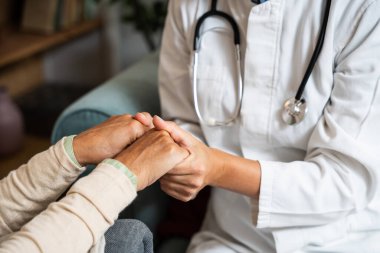 Destekleyici kadın bakıcı, olgun büyükannenin elini tutuyor, hastayı evinde ziyaret ediyor, ilgili kadın doktor, yaşlı büyükanneye destek oluyor, danışmanlık yapıyor veya yardım ediyor, yaşlı sağlık hizmetleri kavramı.