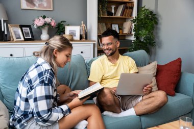 Evdeki oturma odasındaki kanepede dizüstü bilgisayarı ve kitabı olan bir kadının yanında çalışan mutlu genç adam. Serbest çalışan erkek bilgisayar kadını üzerinde çalışıyor ve roman okuyup dinleniyor. Çift hedef kavramı