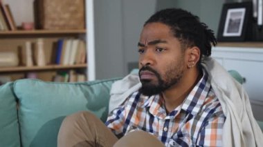 Young depressed African American man sitting on sofa with crossed arms. Racism victim for skin color black male suffering from depression after being fired from work Job lost and mental health concept