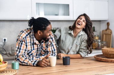 Genç çift sabah işe gitmeden önce mutfakta birlikte kahve içiyorlar. Duygusal insanlar boş vakitlerini çay ve sohbetle geçirirler..