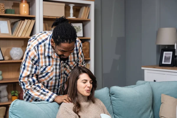 Mixed race couple African American man and white woman, male massage his girlfriend or wife in her menstrual period while sitting at home. Love, support and respect in relationship or marriage concept