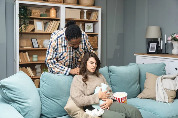 Mixed race couple African American man and white woman, male massage his girlfriend or wife in her menstrual period while sitting at home. Love, support and respect in relationship or marriage concept