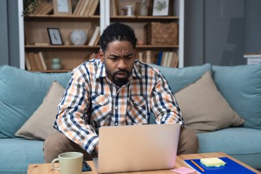 Odaklanmış genç Afrikalı Amerikalı serbest iş adamı çalışması internetten bilgisayardan webinar podcast izliyor eğitim kursu konferansını dinliyor notlar alıyor çalışma masasında e-öğrenim konseptine oturuyor.