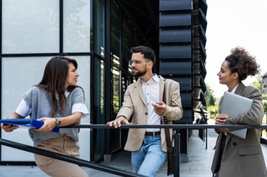 Bir grup genç iş adamı ürün stratejisi uzmanı ofis binası önünde iş aramak için insan kaynaklarından işverenle görüşmeyi bekliyor. İş adamları ve iş kadınları tartıştılar