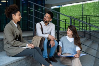 Bir grup genç iş adamı ürün stratejisi uzmanı ofis binası önünde iş aramak için insan kaynaklarından işverenle görüşmeyi bekliyor. İş adamları ve iş kadınları tartıştılar