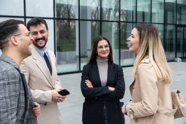 Bir grup genç iş adamı ürün stratejisi uzmanı ofis binası önünde iş aramak için insan kaynaklarından işverenle görüşmeyi bekliyor. İş adamları ve iş kadınları tartıştılar