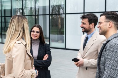 Bir grup genç iş adamı ürün stratejisi uzmanı ofis binası önünde iş aramak için insan kaynaklarından işverenle görüşmeyi bekliyor. İş adamları ve iş kadınları tartıştılar