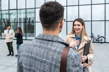 Bir grup genç iş adamı ürün stratejisi uzmanı ofis binası önünde iş aramak için insan kaynaklarından işverenle görüşmeyi bekliyor. İş adamları ve iş kadınları tartıştılar