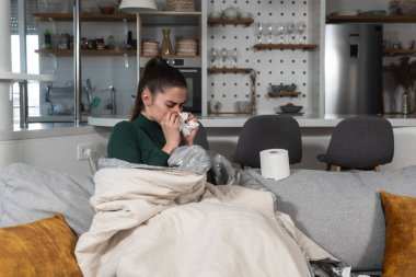 Battaniyeye sarılı genç hasta bir kadın burnunu kağıt mendille siler, hastalanır çünkü evinde ısıtma ve şehrin ısıtma sisteminde bozulma için parası yoktur..