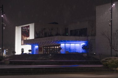 Novi Sad, Sırbistan. Ocak - 15. 2024. Sırp Ulusal Tiyatrosu 'nun modern binasının gece manzarası, kar yağışlı kış gününde eski Novi Sad şehir merkezinde yer alıyor. Düzenleyici resim