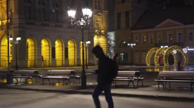 Sırbistan 'ın Novi Sad kentinde binalar ve insanların kar altında yürüdüğü soğuk kış gününde kent hayatının gece görüntüsü. 