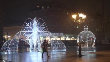 Sırbistan 'ın Novi Sad kentinde binalar ve insanların kar altında yürüdüğü soğuk kış gününde kent hayatının gece görüntüsü. 