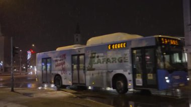 Novi Sad, Sırbistan. Ocak - 15. 2024. Sırbistan 'ın Novi Sad kentinde, binalar ve insanların kar altında yürüdüğü soğuk kış günündeki şehir yaşamını gece görüşü. Yazı