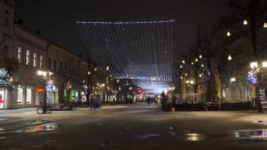 Sırbistan 'ın Novi Sad kentinde binalar ve insanların kar altında yürüdüğü soğuk kış gününde kent hayatının gece görüntüsü. 