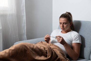 Battaniyeye sarılı genç hasta bir kadın burnunu kağıt mendille siler, hastalanır çünkü evinde ısıtma ve şehrin ısıtma sisteminde bozulma için parası yoktur..