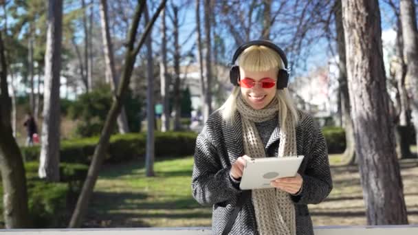 Счастливая Девушка Хиппи Просматривает Планшет Слушает Музыку Наушниками Стоящими Парке — стоковое видео