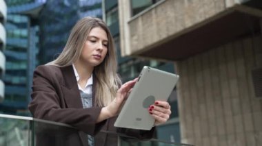 Genç iş kadını motivasyon konuşmacısı yaşam koçu ofis binasının önünde dijital tabletle personel toplantısına hazırlanıyor. İş adamı ürün stratejisi uzmanı bekliyor.