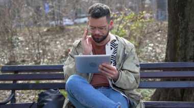 Genç serbest göçmen hippi kuşağı parkta oturmuş e-postaları okuyor iş ekonomisi istatistiklerini kontrol ediyor ve sinirleniyor. Ciddi bir iş adamı. Küçük bir şirket sahibi tatilde.
