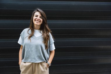 Ofis binasının önünde duran başarılı iş kadınının portresi. Eğitimli bağımsız kadın takım lideri iş adamı siyah duvara karşı poz veriyor..